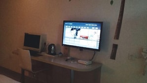 A small hotel room with a desk, a television, and a bed. - Liudianban Inn (Dongguan Dalang) (Dongguan)