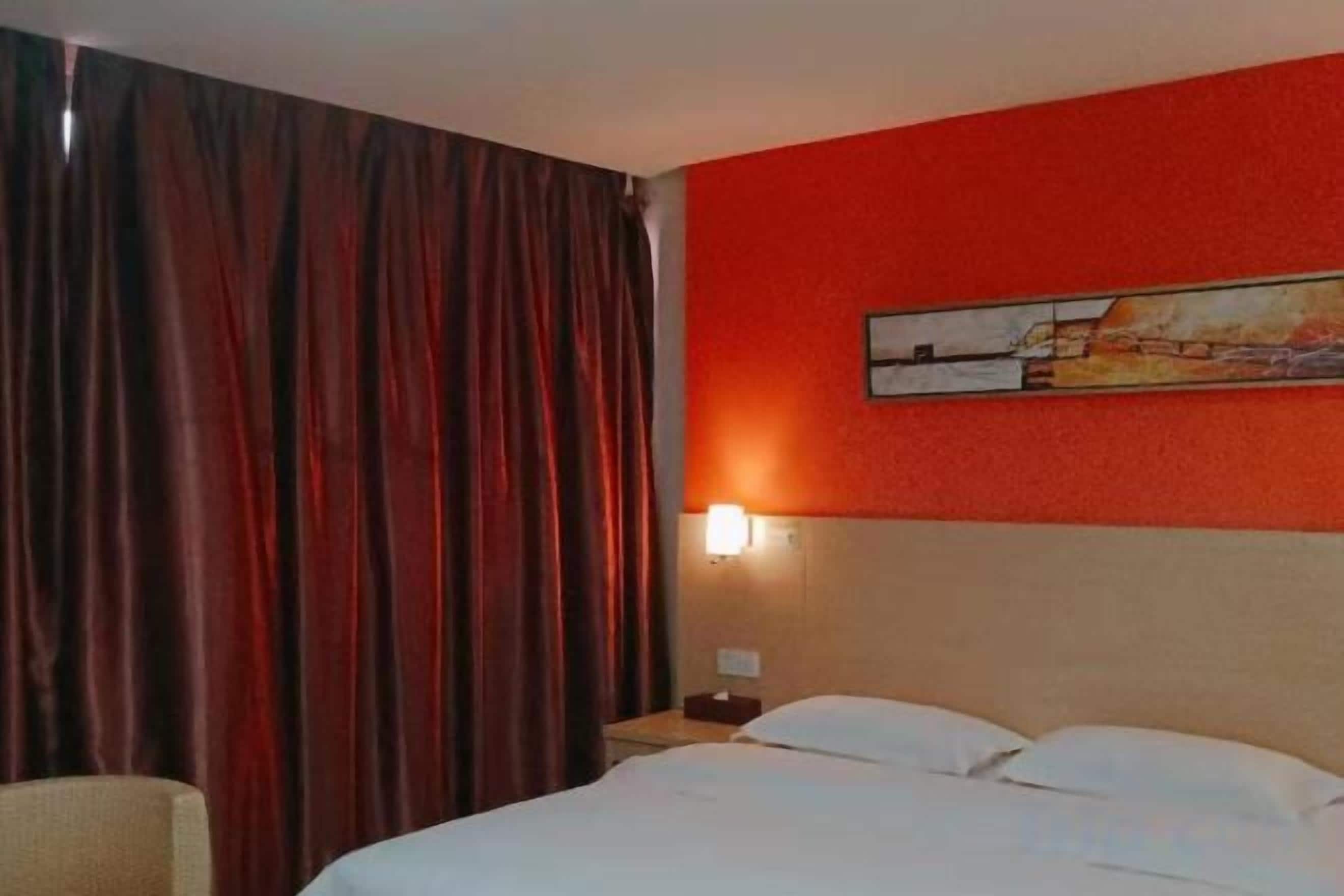Una habitación de hotel con una cama, una mesita de noche, una lámpara y un cuadro en la pared.