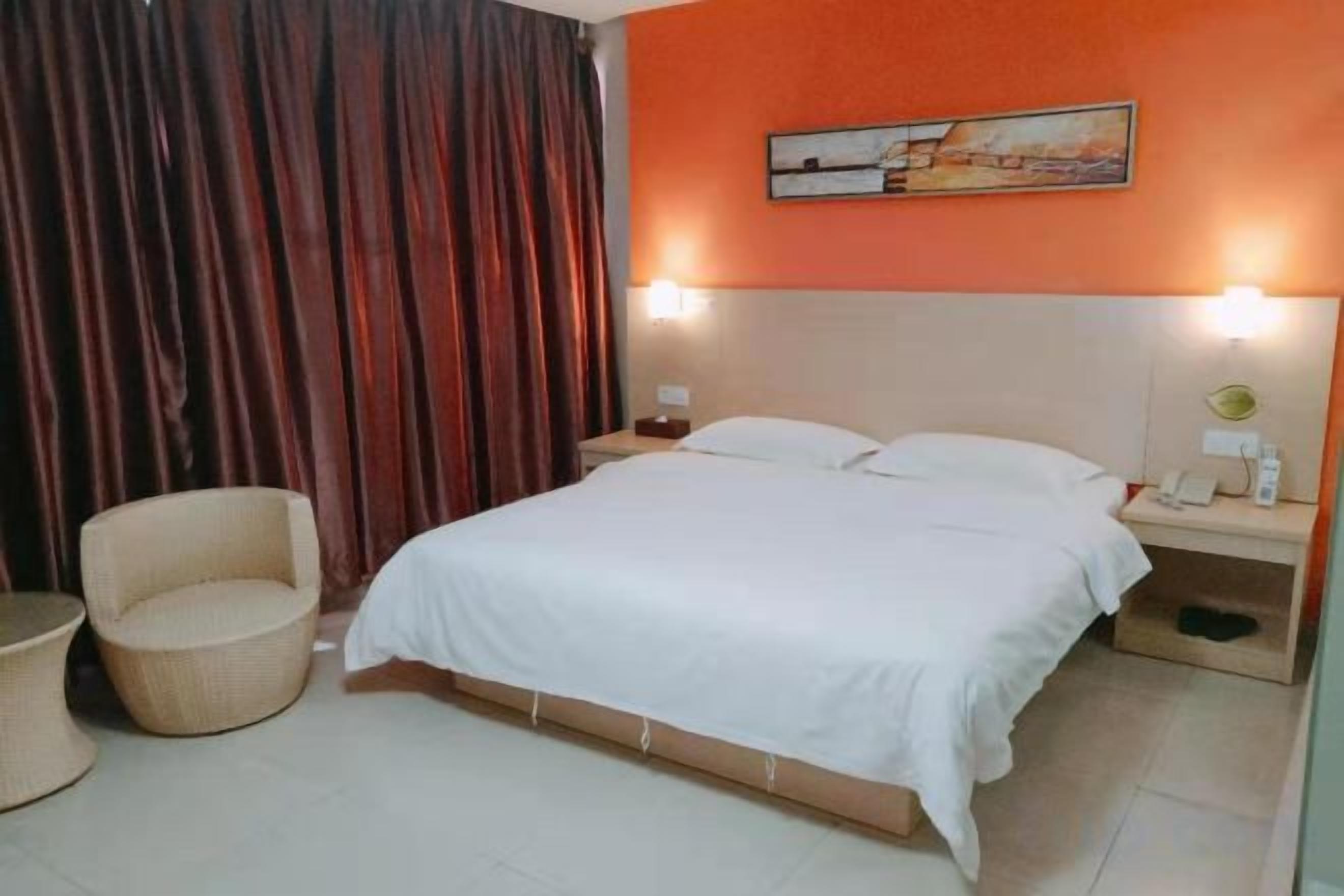 Una habitación de hotel con una cama, una mesita de noche, una silla y un cuadro en la pared.