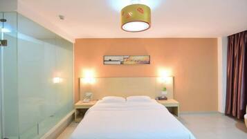 A hotel room with a bed, bedside tables, a nightstand, a painting on the wall, and a glass shower enclosure.