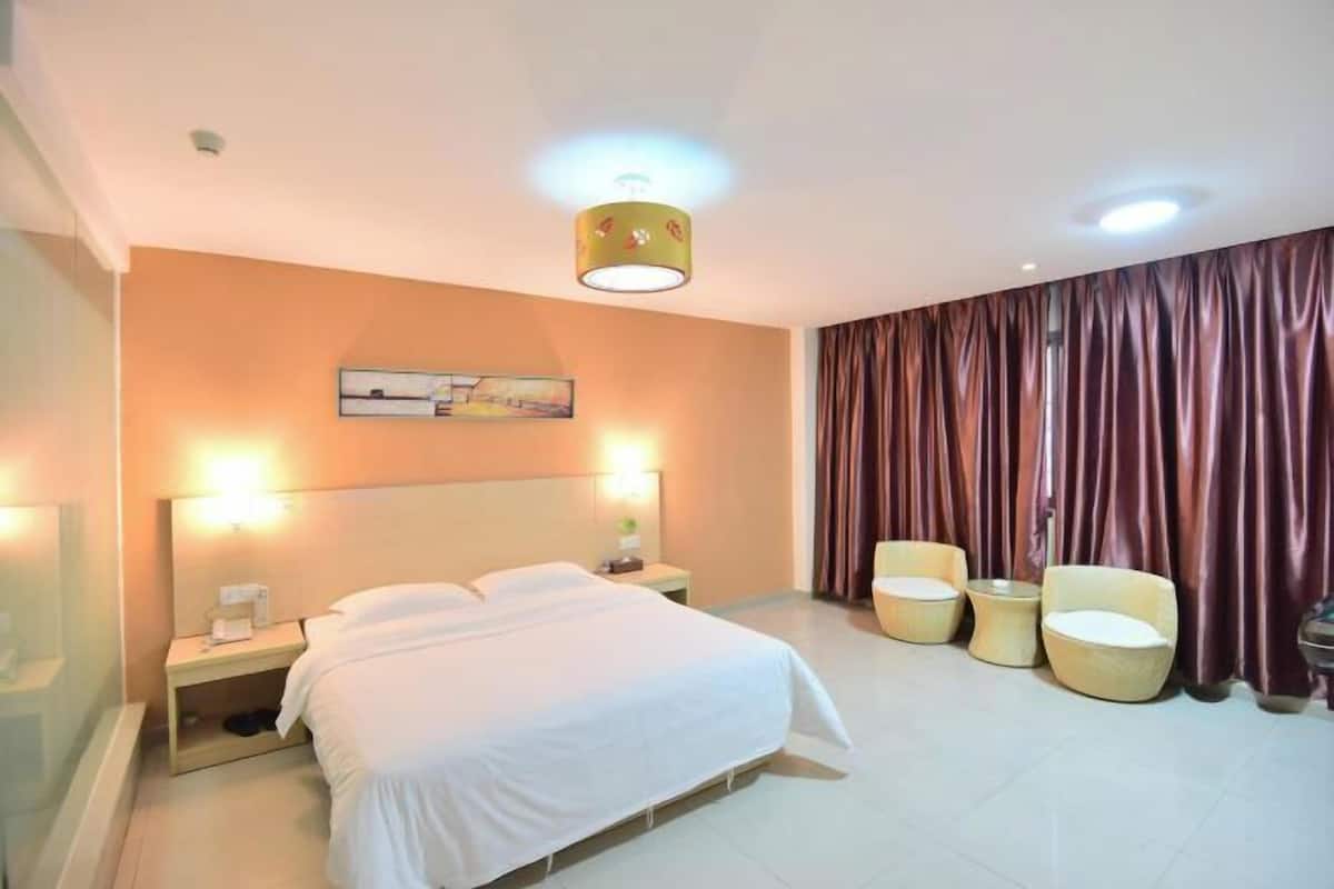 A hotel room with a bed, bedside lamps, a nightstand, a painting on the wall, and a curtain.