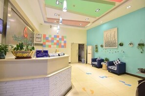 A reception area with a counter, plants, and a colorful wall art piece.
