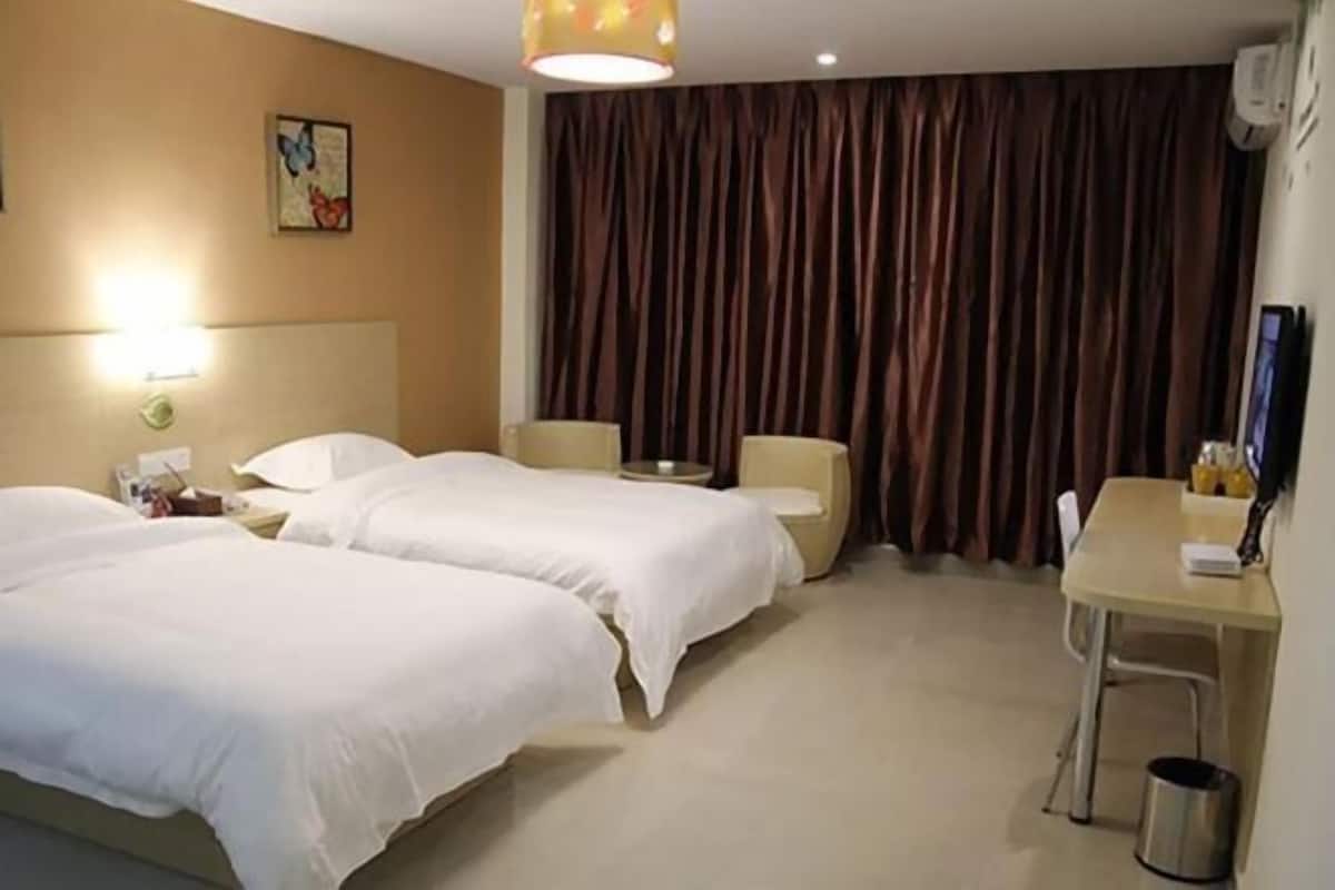 A hotel room with two beds, a desk, and a chair.