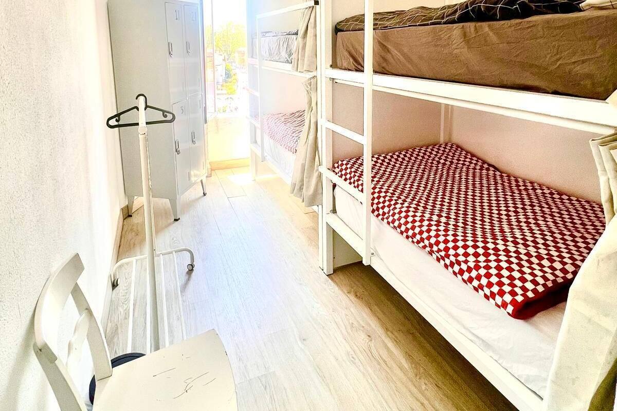 A dormitory room with bunk beds, a desk, and a chair.