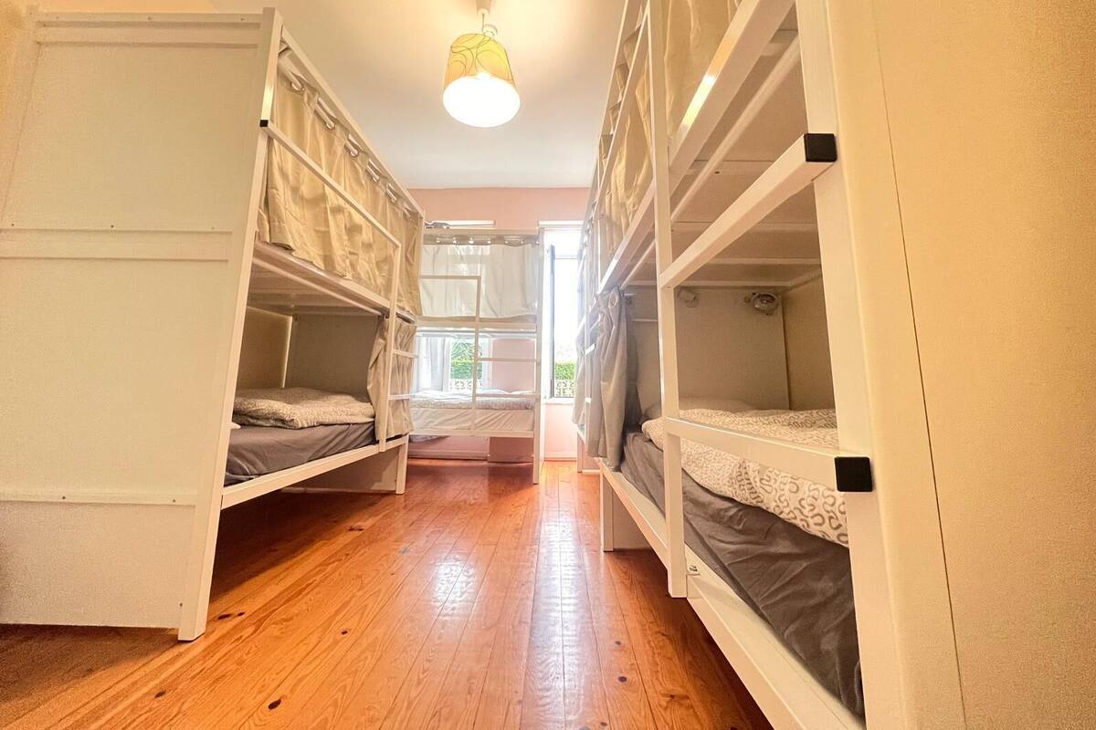 A room with bunk beds, wooden flooring, and a ceiling light.