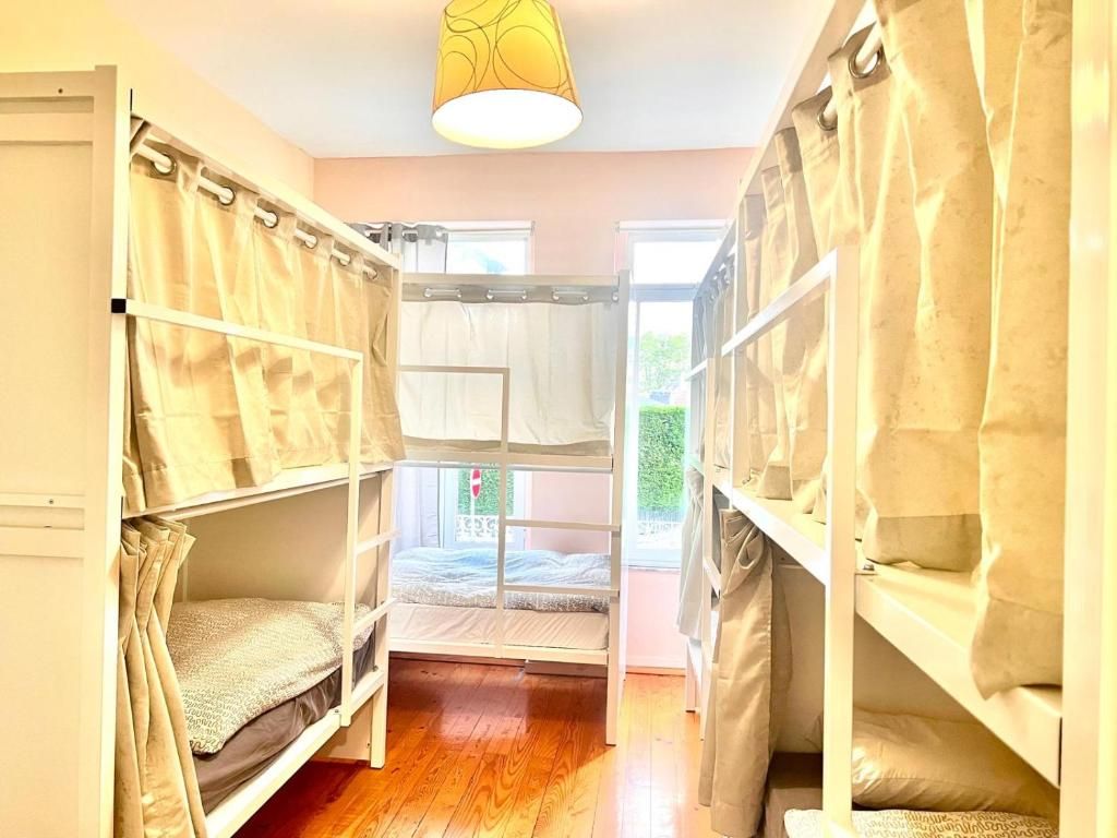 Une chambre avec un lit superposé, une fenêtre, un luminaire suspendu et un plancher en bois.