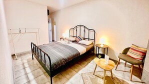 Ein Schlafzimmer mit Bett, Nachttischen, einem Sessel und einem kleinen Teppich.
