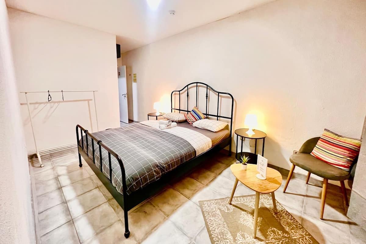 A bedroom with a bed, bedside tables, a chair, and a small rug.