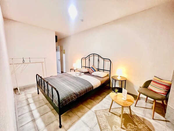 A bedroom with a bed, bedside tables, a chair, and a small rug. - SwissPorto Guest House (Porto)