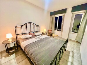 Une chambre à coucher bien rangée, avec un lit, des tables de chevet et une fenêtre.