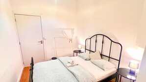 A single bed with a metal frame, a bedside table with a lamp, and a wardrobe. - SwissPorto Guest House (Porto)