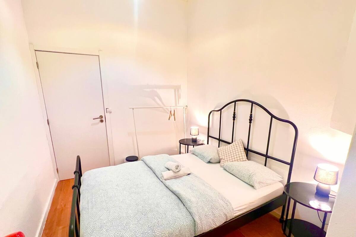 A single bed with a metal frame, a bedside table with a lamp, and a wardrobe.