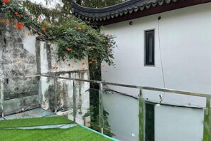 A courtyard with a white building, a glass railing, and a tree with orange flowers. - Shiguangli Inn (Suzhou)