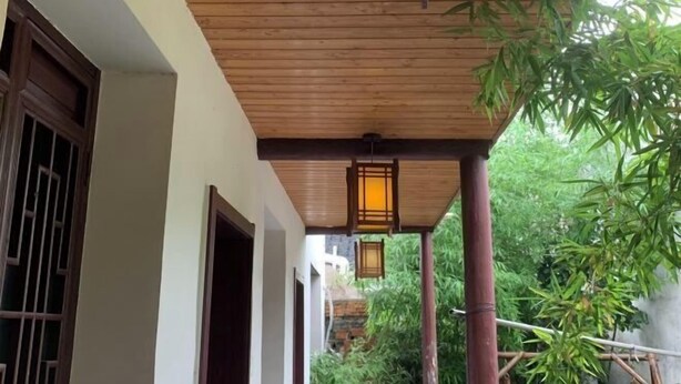 A wooden ceiling with a lantern, a bamboo plant, and a stone wall. - Shiguangli Inn (Suzhou)