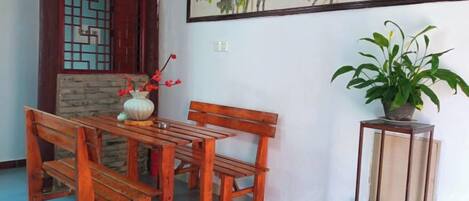 A wooden dining table with benches, a vase with flowers, and a potted plant on a stand.