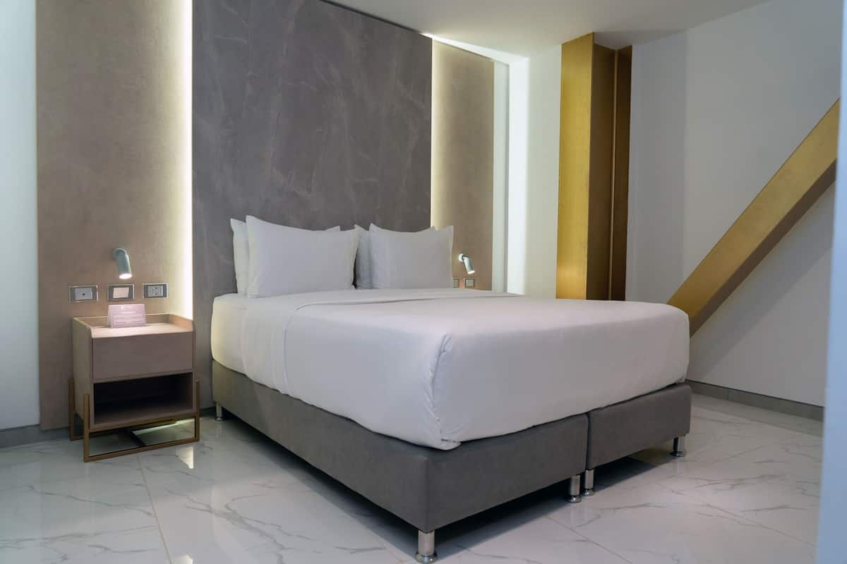 A modern bedroom with a large bed, a bedside table, and a nightstand.