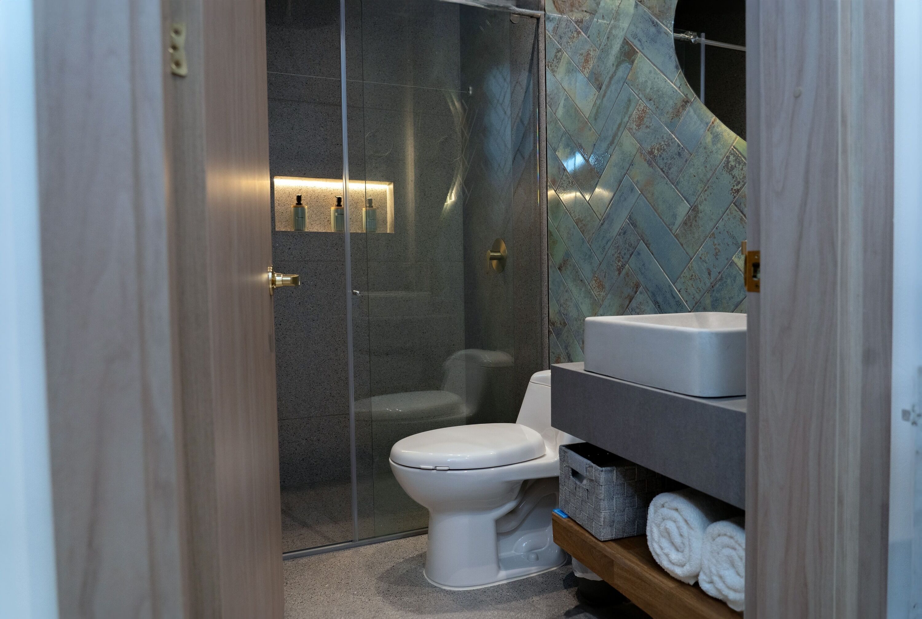Ein modernes Badezimmer mit Duschkabine aus Glas, einer weißen Toilette und einem Waschtisch mit Spüle und Stauraum.