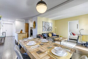 A dining area with a wooden table set for four, a sofa, and a painting on the wall. - Charlotte Luxury Townhomes (Charlotte)