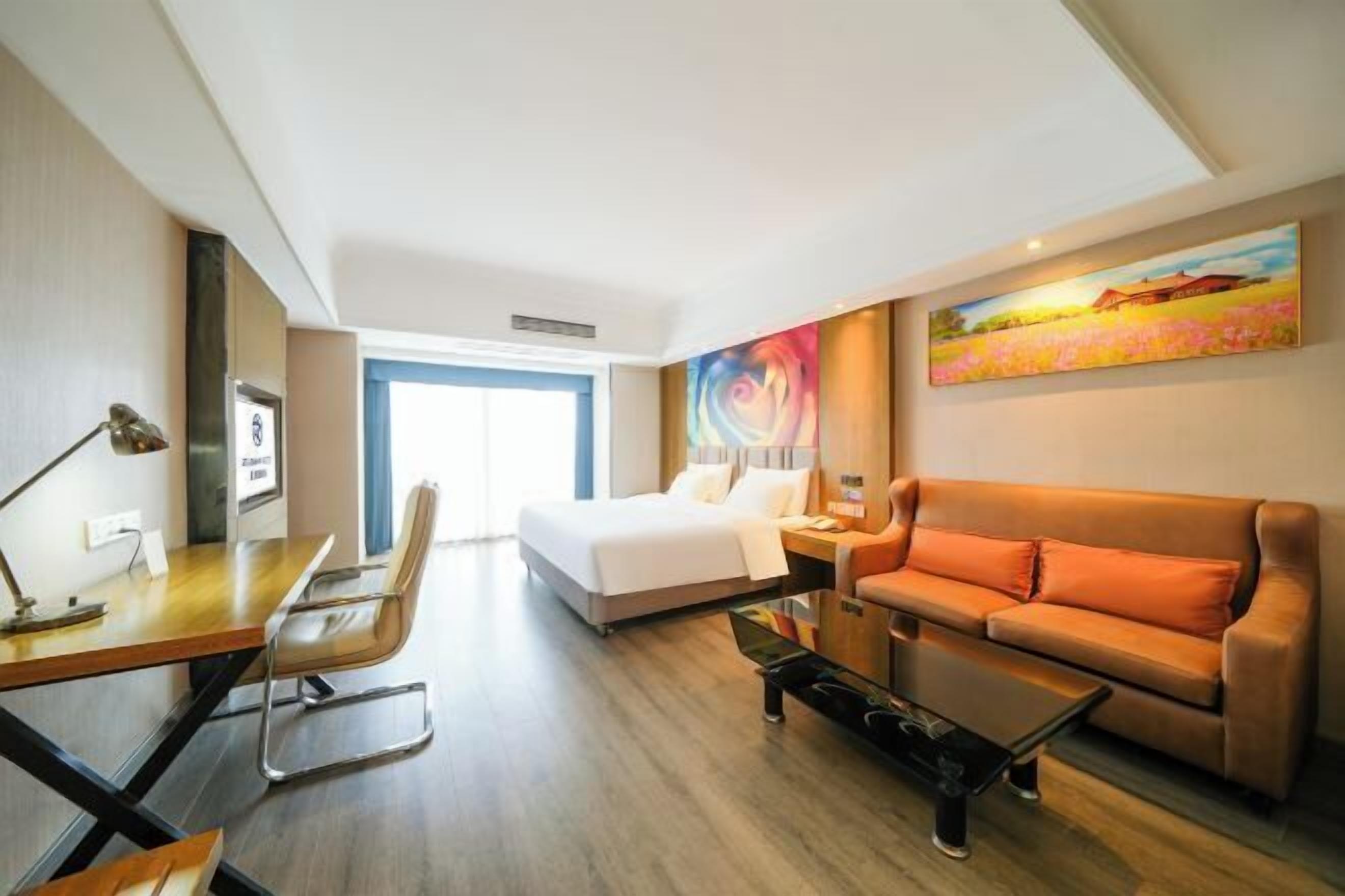 A hotel room with a bed, a sofa, a desk, and a chair.