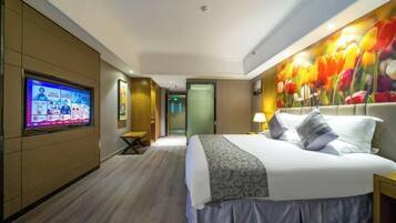 Habitación de hotel con una cama grande, un televisor en la pared y un mural floral.