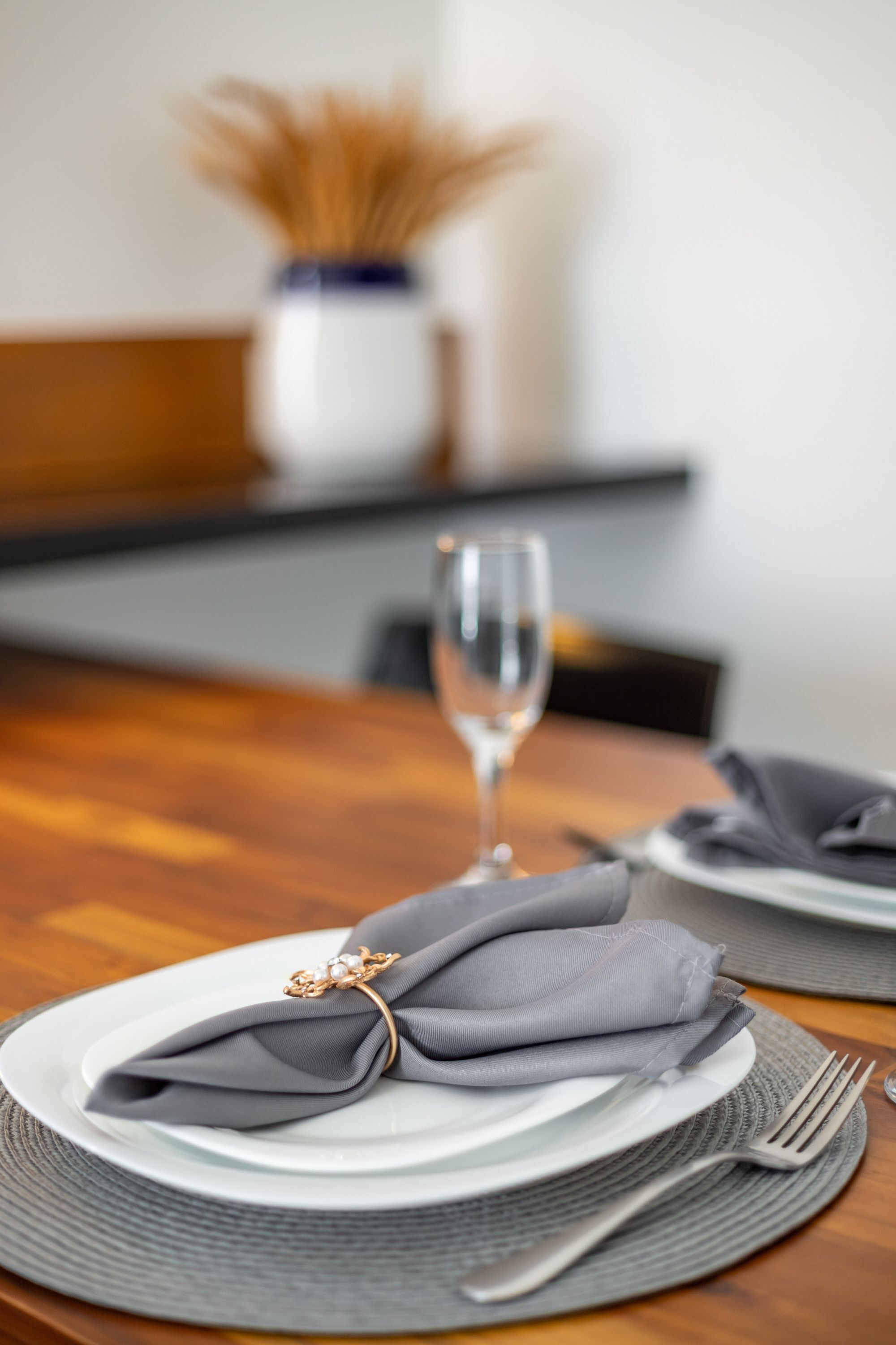 A neatly set dining table with a folded napkin, a glass of water, and a fork.