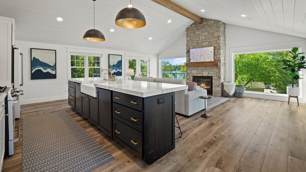 Una cocina amplia con una isla grande, suelo de madera e iluminación colgante.