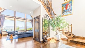 A spacious living room with a large window, a staircase, and a dining area.