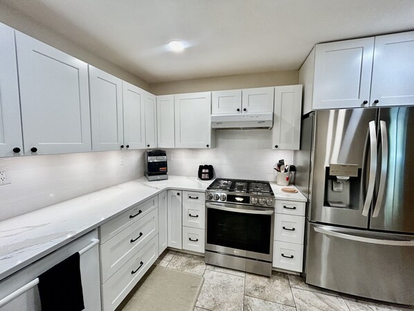 A modern kitchen with white cabinets, a stainless steel refrigerator, an LG gas stove, and a coffee maker. - Sprawling ranch W/ HUGE Yard, Patio, & W/D (Wichita)