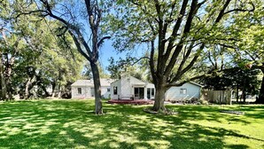 A house with a front porch, a lawn, and trees in the background. - Sprawling ranch W/ HUGE Yard, Patio, & W/D (Wichita)