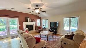 A spacious living room with a fireplace, comfortable seating, a television, and large windows. - Sprawling ranch W/ HUGE Yard, Patio, & W/D (Wichita)