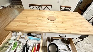 A wooden dining table with two open drawers below it, containing kitchen utensils and cookware. - Sprawling ranch W/ HUGE Yard, Patio, & W/D (Wichita)