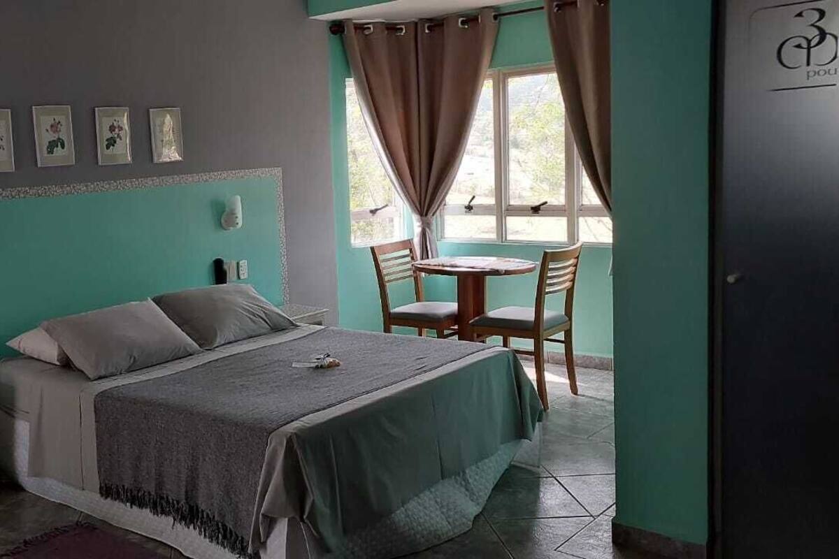 A bedroom with a bed, bedside table, and a window with curtains.
