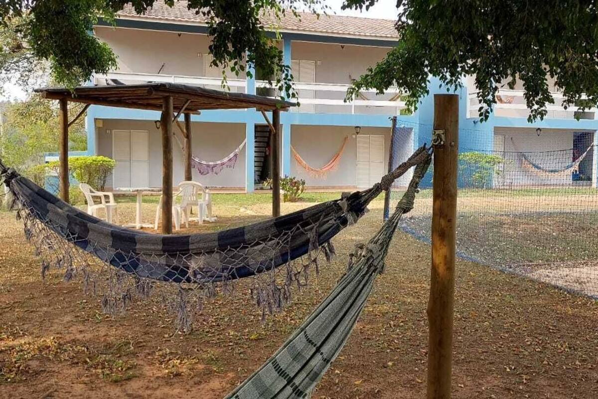 A hammock tied between trees in a courtyard with a building in the background.