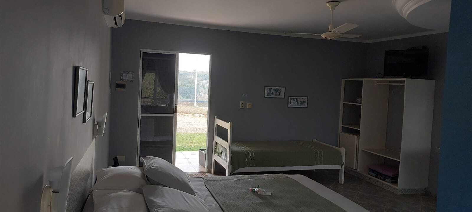 Une pièce comprenant un lit, une armoire et une porte donnant sur un espace extérieur.