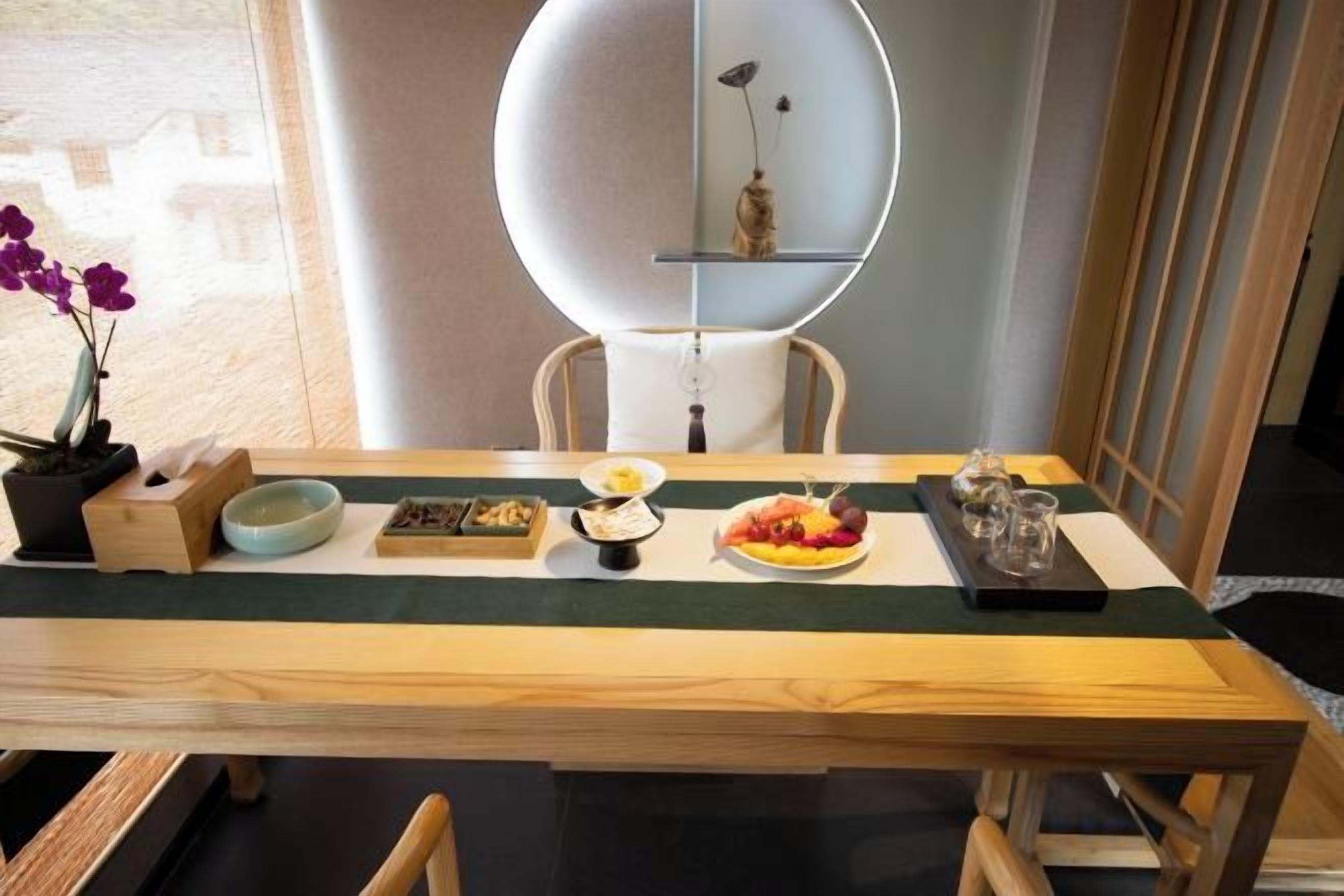 Una mesa de comedor con varios platos, un florero con flores y una estantería decorativa.