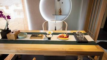 Una mesa de comedor con varios platos, un florero con flores y una estantería decorativa.