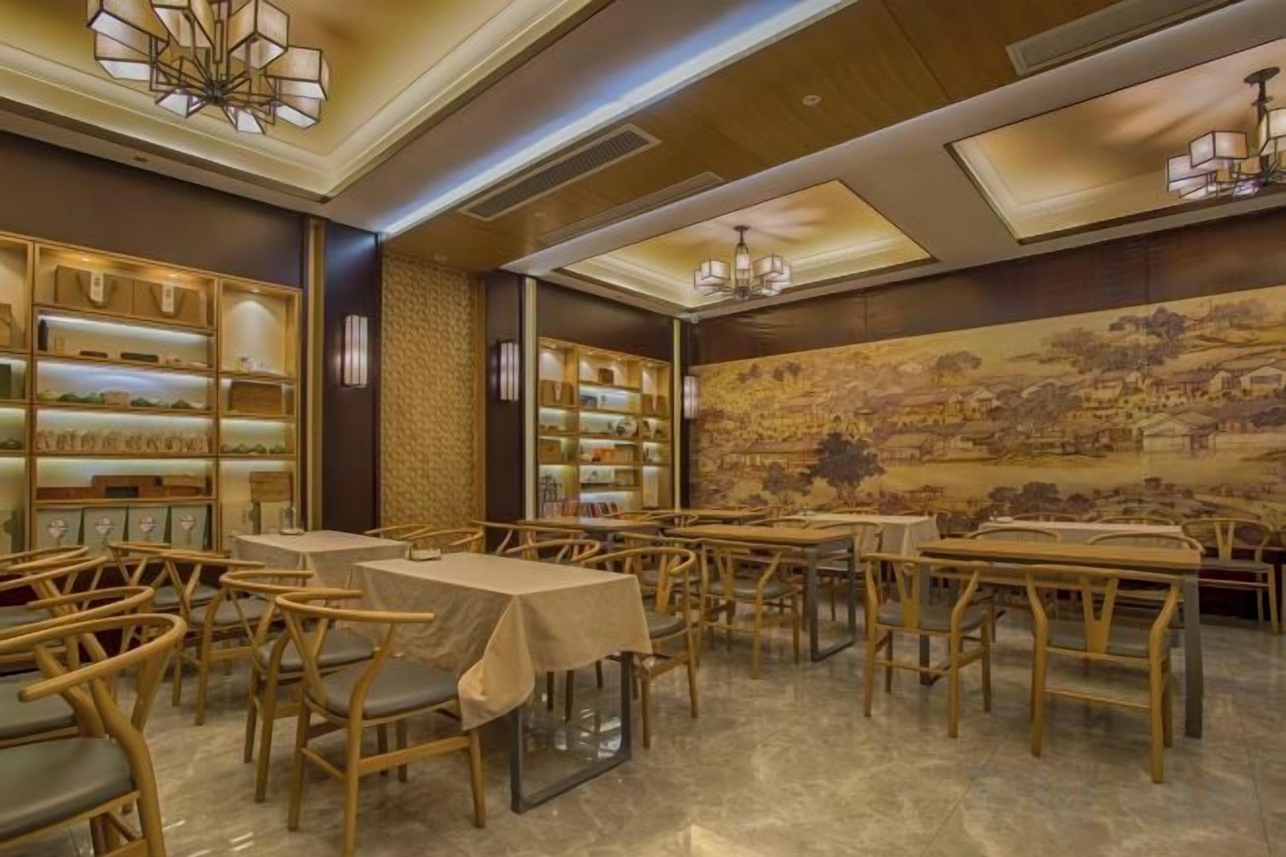 Un comedor con mesas y sillas, una pared con un mural, y estantes con objetos a la izquierda.