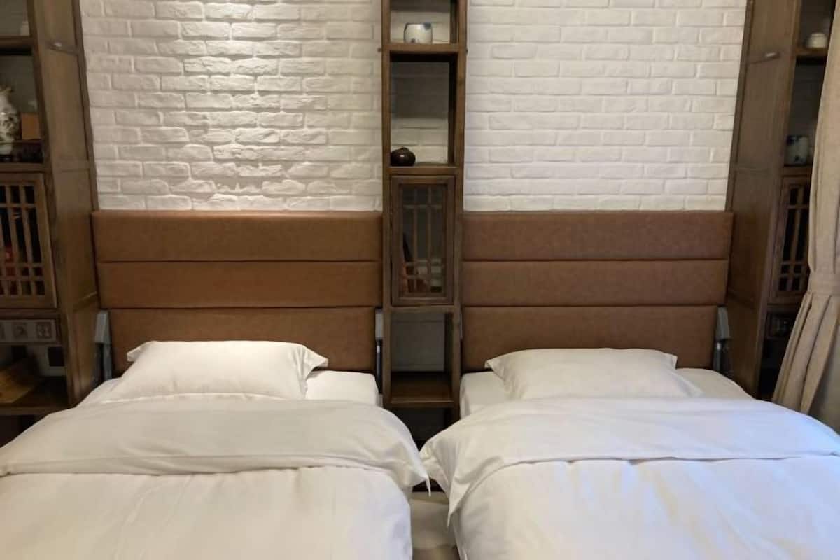A hotel room with two beds, a brick-patterned wall, and wooden headboards.