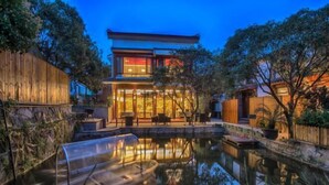 A modern house with a reflective pool, wooden deck, and outdoor seating area. - West Lake Teavilla (Hangzhou)