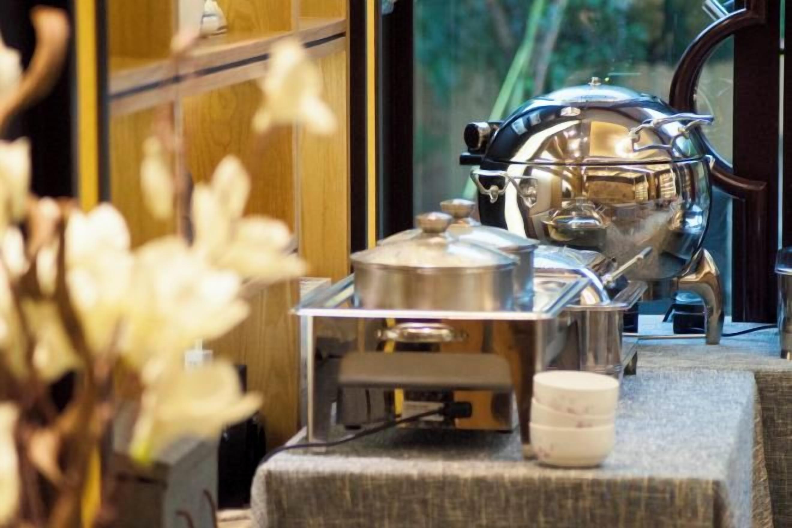 Una cafetera espresso antigua sobre una mesa con un recipiente pequeño y una vela.