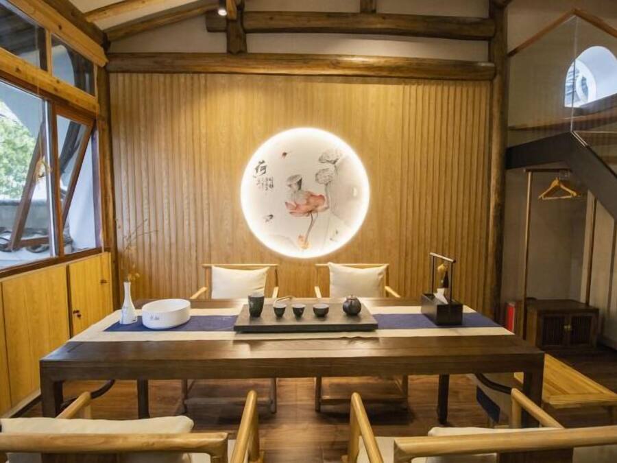 A traditional wooden dining table with a circular light fixture above it, surrounded by chairs.
