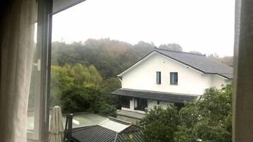 Vista de una casa con techo inclinado y fachada blanca, rodeada de árboles.
