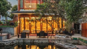 A traditional-style building with a wooden facade, a glass entrance, and a small pond with a boat. - West Lake Teavilla (Hangzhou)