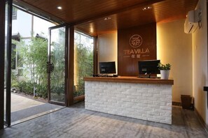 Un comptoir d’accueil avec un revêtement en briques blanches, un téléviseur et un logo placé au-dessus.
