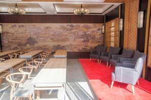 Una stanza con tavoli e sedie, un tappeto rosso e un muro decorato con un murale elaborato.