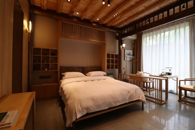 Een slaapkamer met een bed, nachtkastjes, een bureau en een stoel.