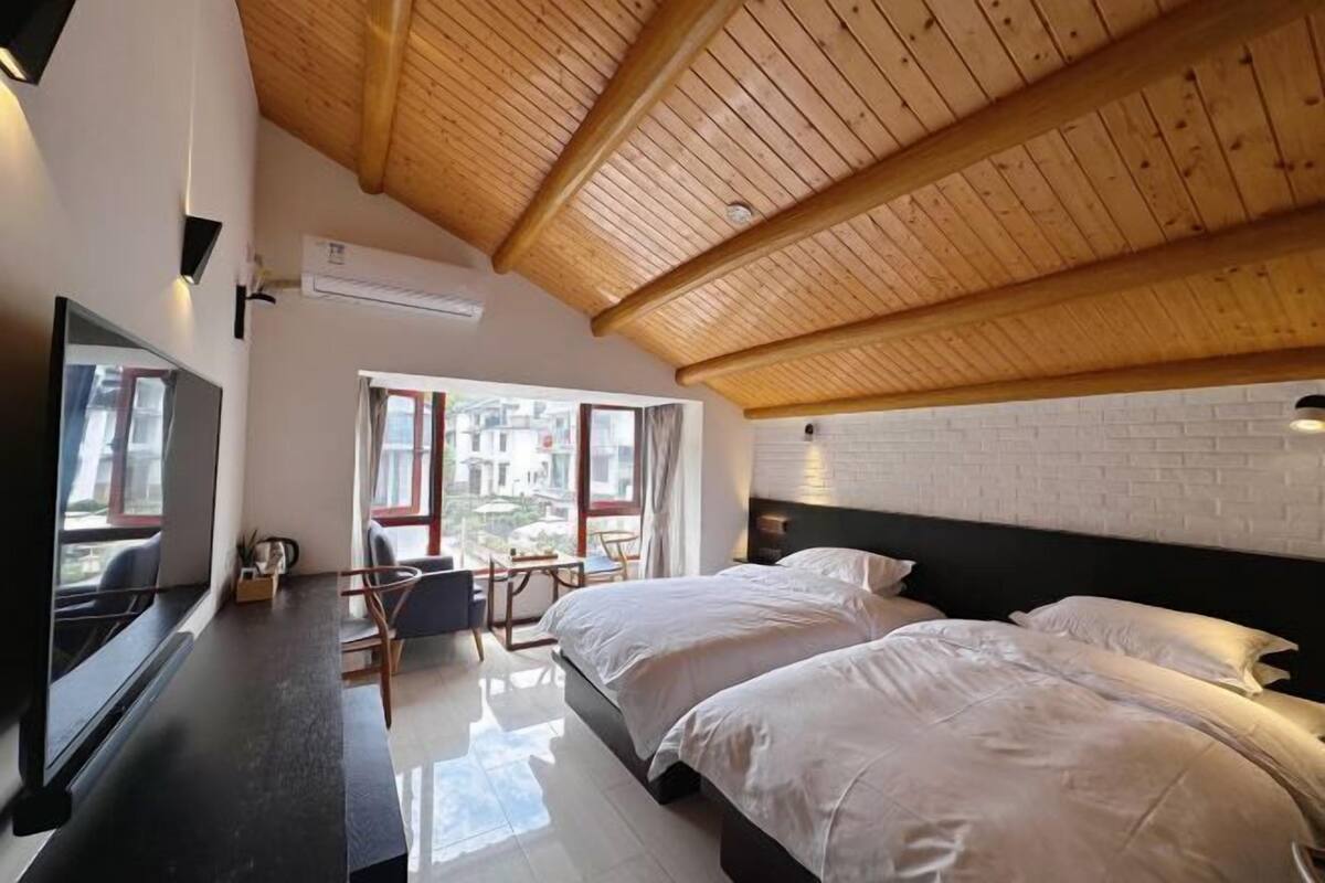 A bedroom with a wooden ceiling, a bed, a desk, and a TV.