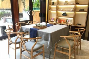 A dining area with a table set for four, surrounded by wooden chairs with cushioned seats. - West Lake Teavilla (Hangzhou)