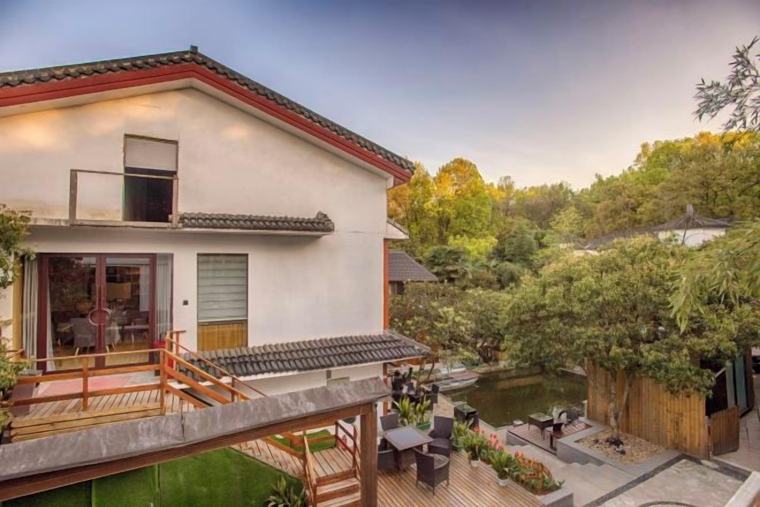 A two-story building with a balcony, a pond, and a wooden deck.