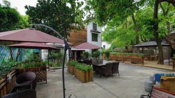 Un patio al aire libre con muebles de mimbre, una mesa de comedor y sombrillas.